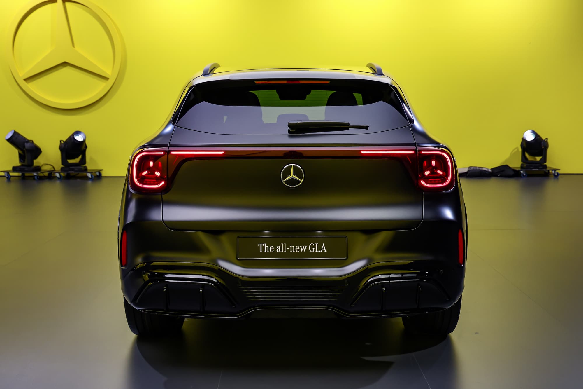 De nieuwe GLA van achteren op een presentatiepodium, rode lichtbalk, gele wand met de Mercedes-ster